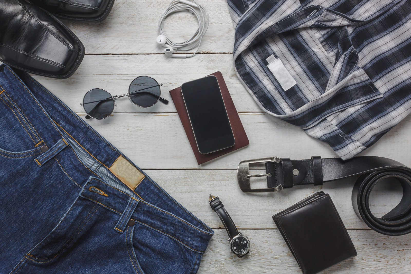Top view accessoires to travel with man clothing concept. shirt, Top view table the mobile phone,shoe,sunglasses,camera,wallet,belt,watch,trousers and shirt on white table background.